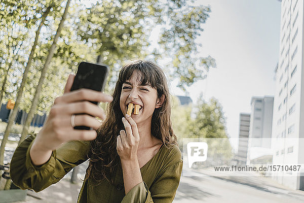 Porträt einer brünetten Frau  die einen Selfie nimmt  Kaninchenzähne mit Pommes Frites