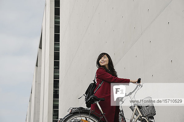 Geschäftsfrau mit Fahrrad im Hintergrund des modernen Gebäudes