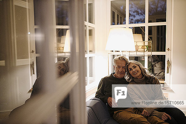 Porträt eines älteren Paares  das sich abends zu Hause auf der Couch entspannt