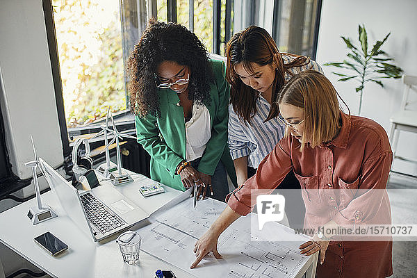 Businesswomen having a meeting in office with wind turbine models on table