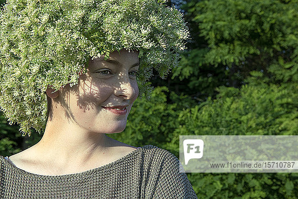 Porträt einer lächelnden jungen Frau mit Blumenkopfbedeckung