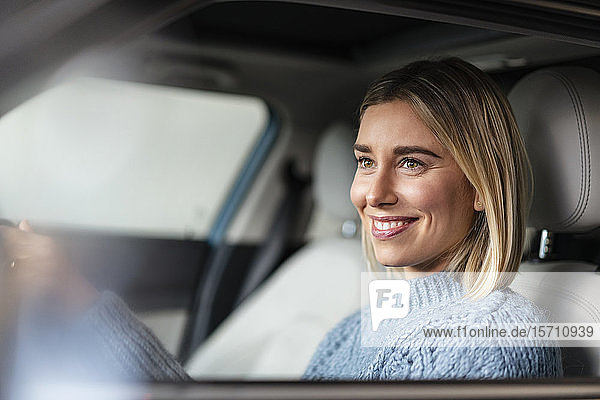 Porträt einer lächelnden jungen Frau am Steuer eines Autos
