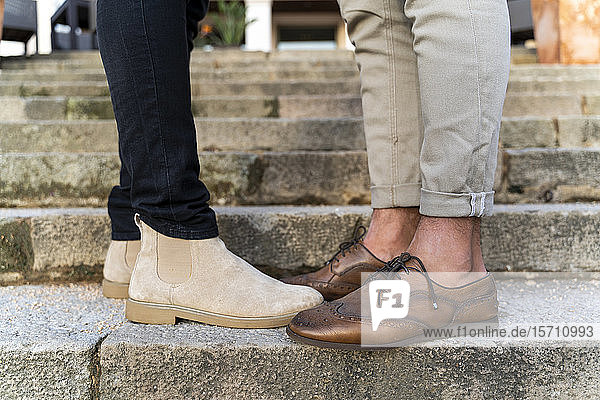 crop view of gay couple wearing leather shoes standing on stairs
