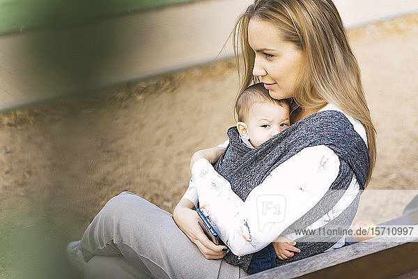 Glückliche Mutter ruht mit dem kleinen Jungen auf einer Parkbank