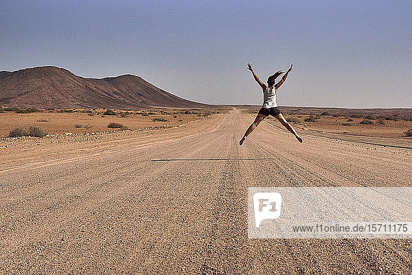 Frau springt mitten auf einen Feldweg  Damaraland  Namibia
