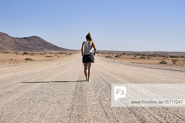 Woman walking in the middle of a dirt road  Damaraland  Namibia