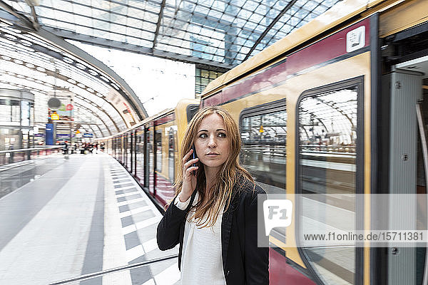 Frau am Telefon beim Aussteigen aus dem Zug  Berlin  Deutschland
