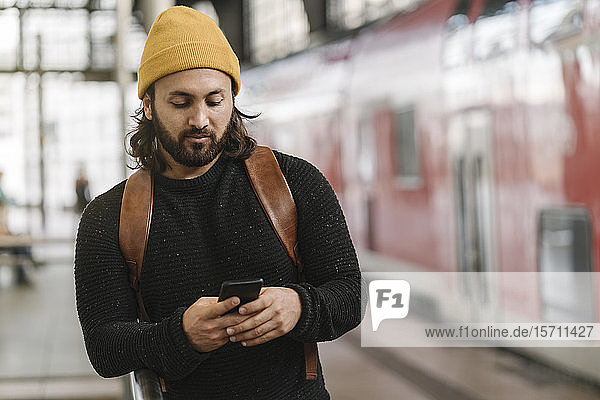 Junger Mann mit Smartphone am Bahnsteig  Berlin  Deutschland