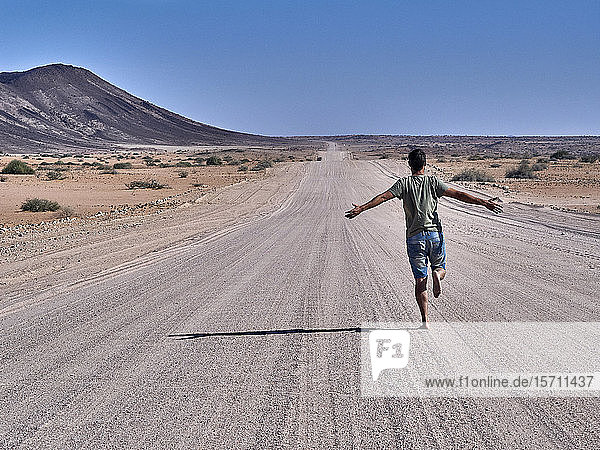 Man running freely on an endless road  rear view  Damaraland  Namibia