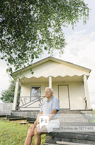 Porträt eines älteren Mannes beim Entspannen vor einem Ferienhaus  Kalvene Lettland