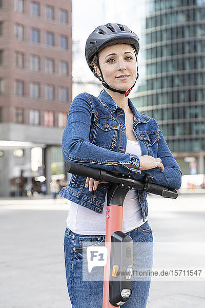 Porträt einer lächelnden Frau mit E-Scooter in der Stadt  Berlin  Deutschland