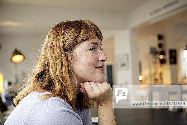 Porträt einer erdbeerblonden jungen Frau mit Nasenpiercing in einem Cafe