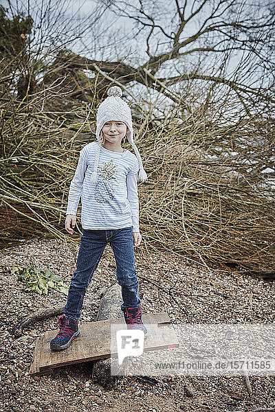 Porträt eines lächelnden kleinen Mädchens mit Pudelmütze  das auf einer Wippe balanciert