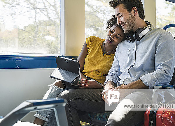 Junges Paar mit Tablette entspannt sich in einem Zug