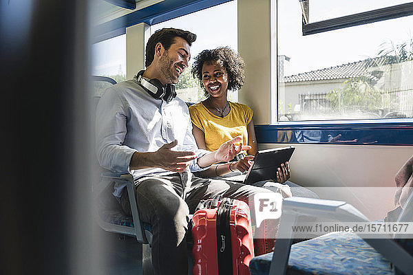 Glückliches junges Paar mit Tablette in einem Zug