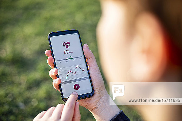 Frau hält Smartphone in der Hand und nutzt Fitness-App