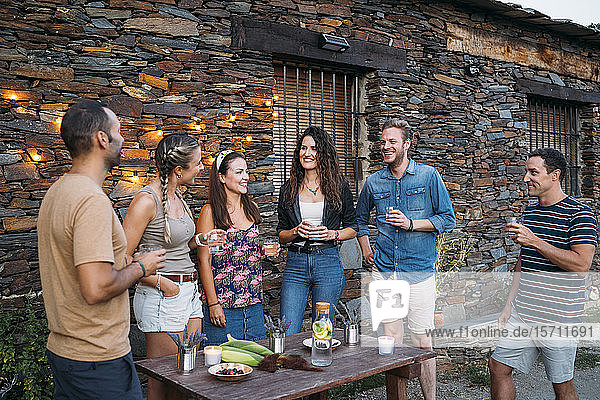 Eine Gruppe von Freunden unterhält sich und trinkt im Freien in einem Steinhaus
