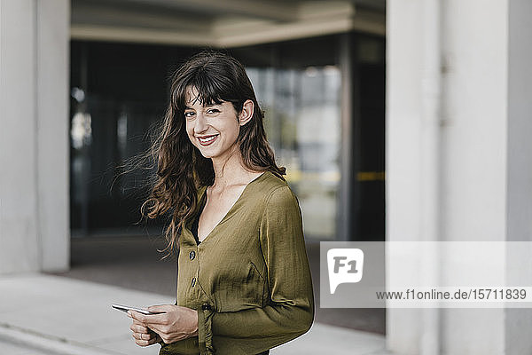 Portrait of smiling brunette woman holding smartphone