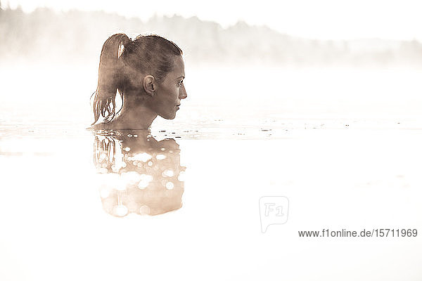 Frau badet im Morgennebel in einem See