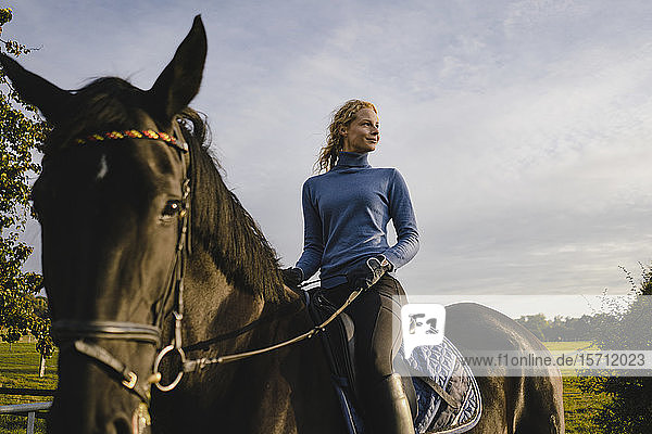 Frau zu Pferd auf einem Feld auf dem Land