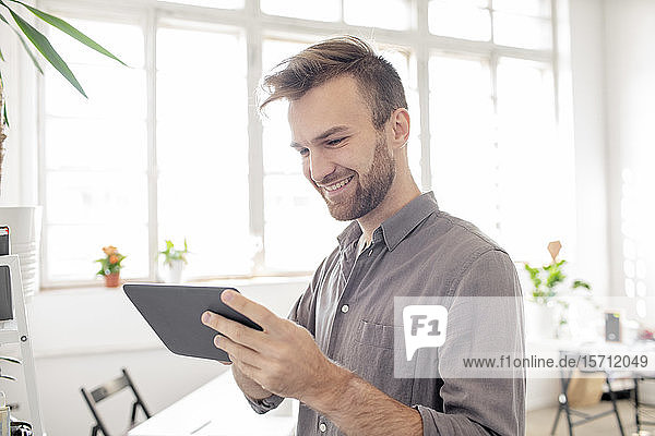 Smiling man using tablet in office