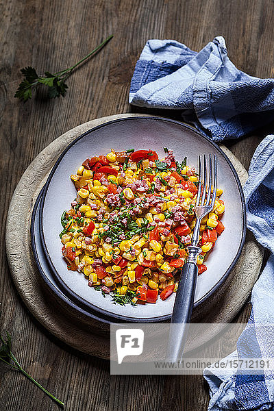 Schüssel warmer Maissalat mit Paprika, Kartoffeln und Schinkenwürfeln