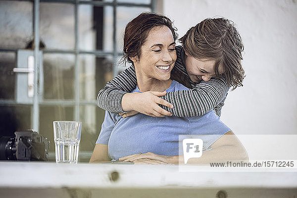 Mädchen umarmt Mutter  sitzt zu Hause