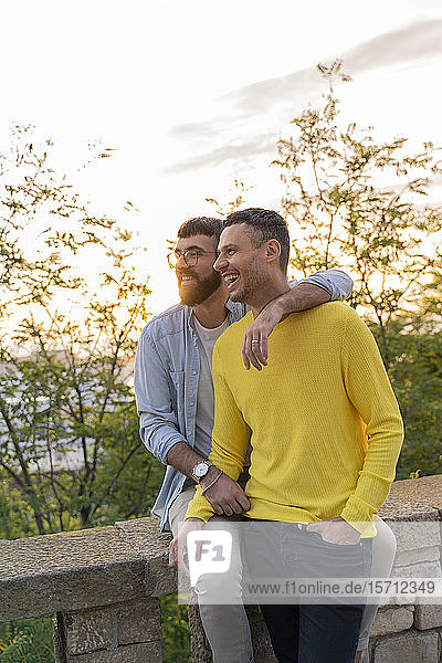 Glückliches schwules Paar bei Sonnenuntergang im Freien