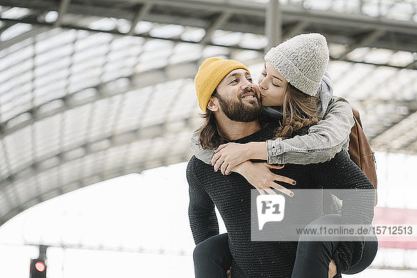 Glückliches junges Paar mit Spaß und Küssen auf dem Bahnsteig  Berlin  Deutschland