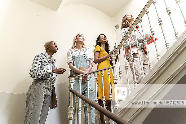 Four confident women walking upstairs in staircase