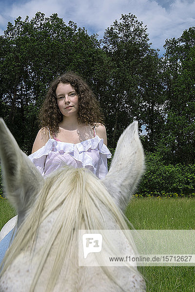 Porträt einer jungen Frau zu Pferd auf einer Wiese