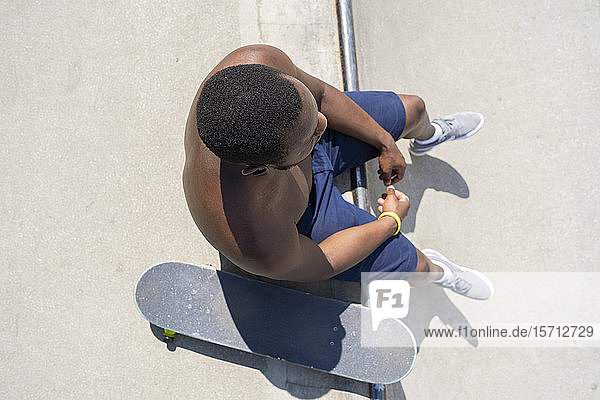 Skateboardfahrer auf Skateboard-Rampe sitzend