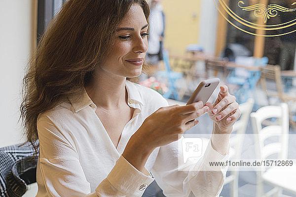 Porträt einer jungen Frau mit Handy in der Hand in einem Cafe