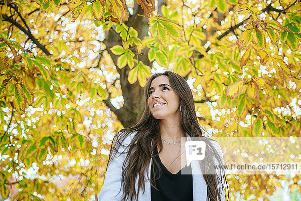 Smiling woman standing under autumnal tree
