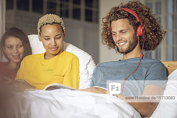 Glückliche Freunde entspannen zu Hause im Bett
