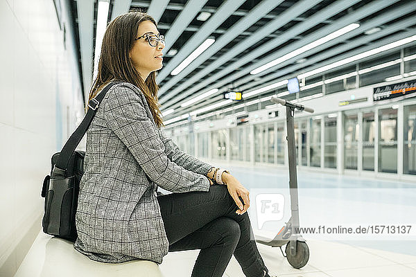 Young businesswoman with e-scooter waiting at the subway station