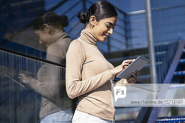 Young woman using tablet on exterior stairs