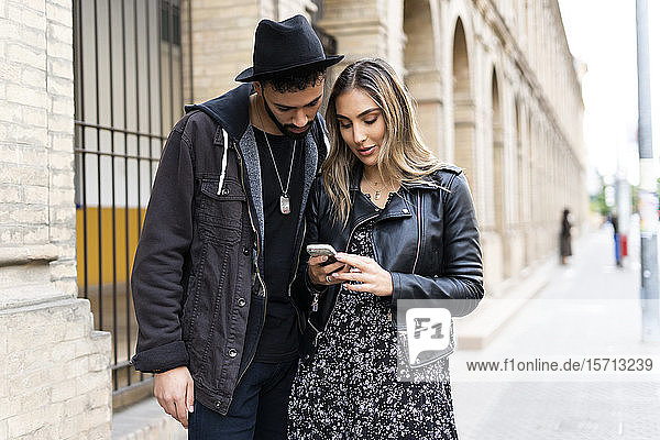 Junges Paar nutzt Smartphone in der Stadt