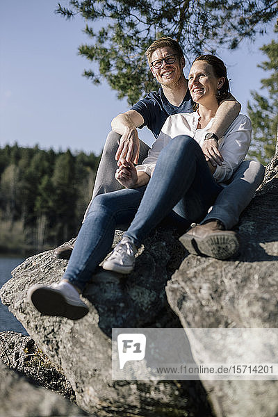 Happy couple sitting on a rock at the lakeside  Forstsee  Carinthia  Austria