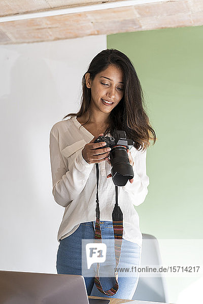Porträt eines lächelnden jungen Architekten mit Kamera und Laptop in einem Atelier