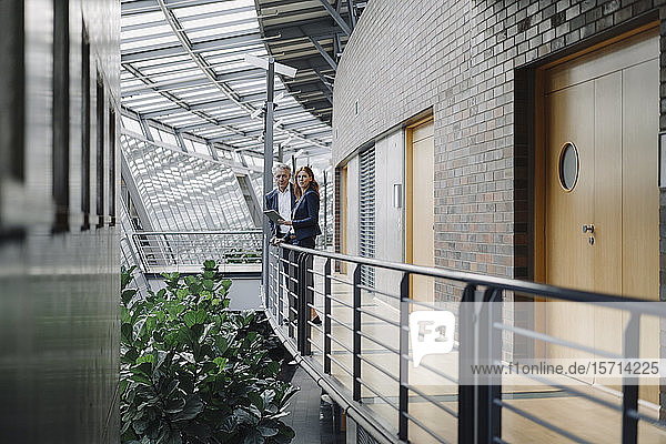 Geschäftsmann und Geschäftsfrau mit Tablett stehend in modernem Bürogebäude