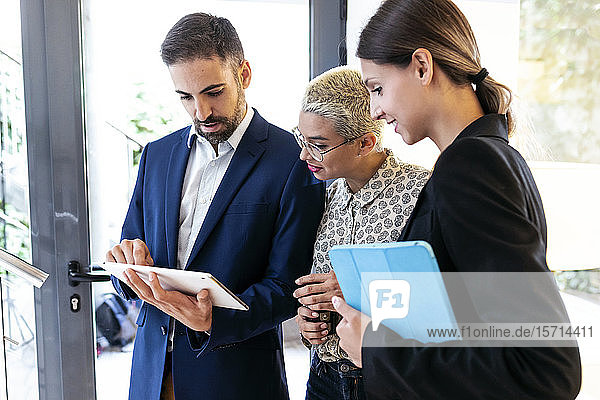Businessman showing tablet to colleagues in office