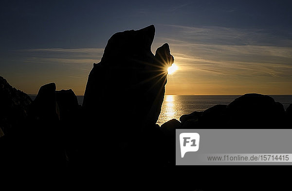 Italy  Province of Sassari  Santa Teresa Gallura  Sun setting behind silhouette of Cape Testa boulder