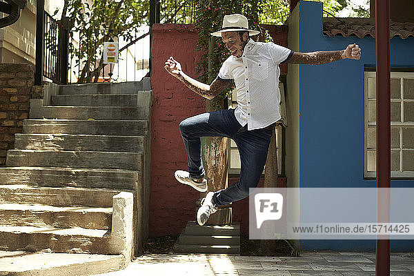 Porträt eines jungen Mannes mit Vitiligo  der einen Hut trägt und auf die Straße springt