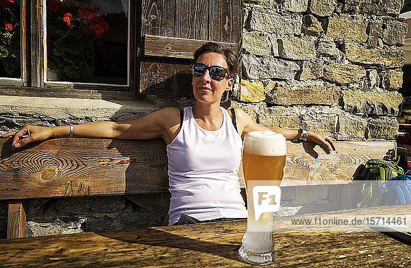 Frau geniesst Sonnenschein und ein Weissbier auf einer Berghütte  Passeiertal  Südtirol  Italien