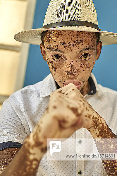 Porträt eines jungen Mannes mit Vitiligo  der einen Hut trägt und seine Faust zeigt