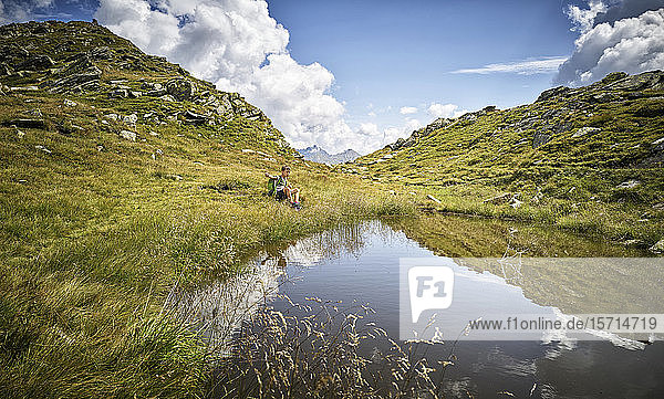 Boy having a break from hiking sitting at a mountain lake  Passeier Valley  South Tyrol  Italy