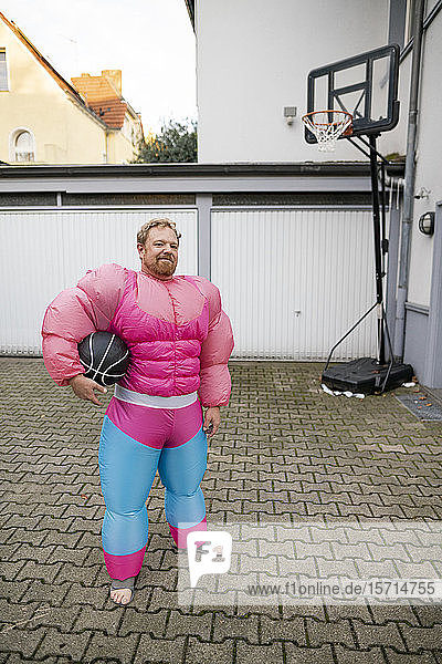 Bildnis eines Mannes mit Basketball in rosa Bodybuilder-Kostüm