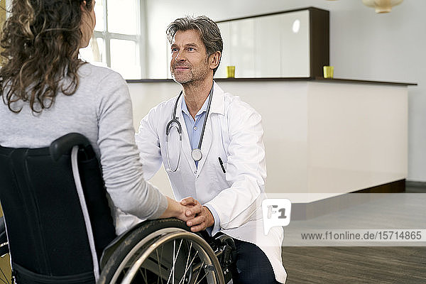 Arzt kümmert sich um Patientin im Rollstuhl