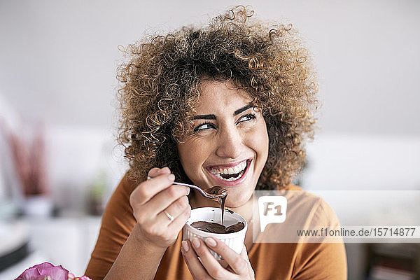 Porträt einer glücklichen Frau  die zu Hause Schokoladencreme isst